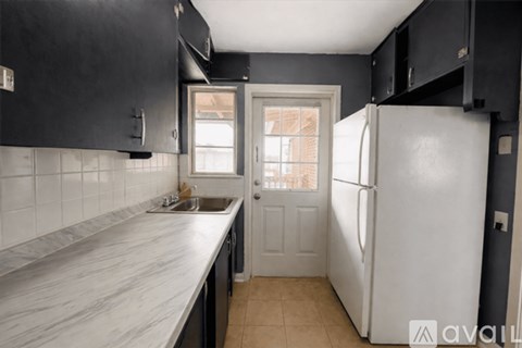A kitchen with black cabinets and a white refrigerator.