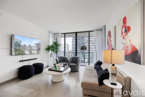 A living room with a couch, chair, ottoman, and a television.