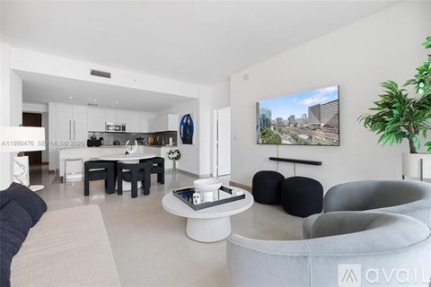 A living room with a grey sofa, a white coffee table, and a TV mounted on the wall.