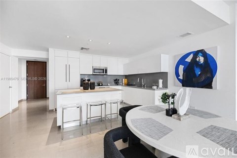 A modern kitchen with white cabinets and a bar area.
