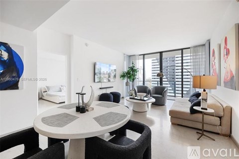 A modern living room with a white table and black chairs.