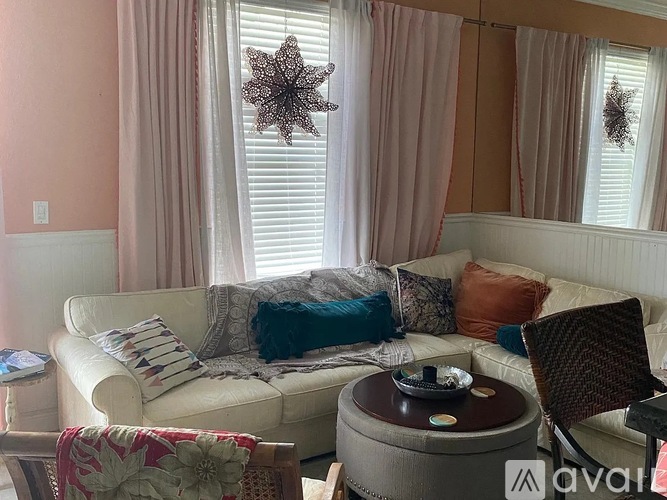 A living room with a white couch, a round table, and a star decoration on the window.
