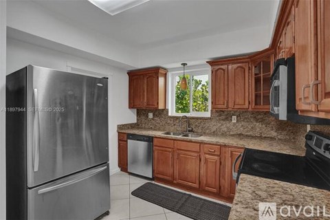 A kitchen with a stainless steel refrigerator and wooden cabinets.