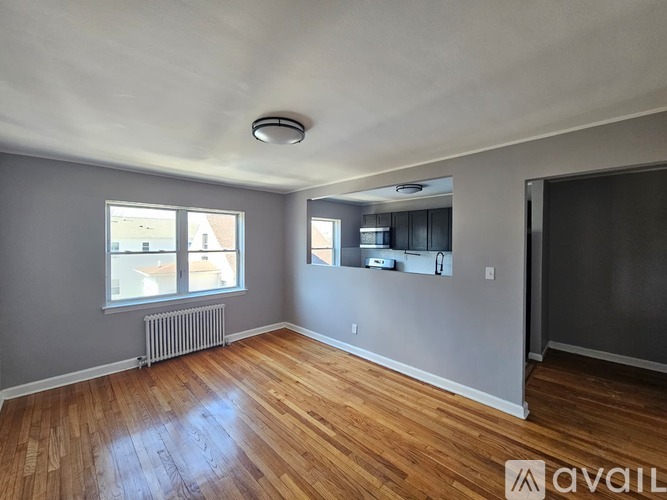A room with wooden floors and a window overlooking a street.
