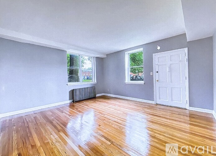 A room with wooden floors and two windows.