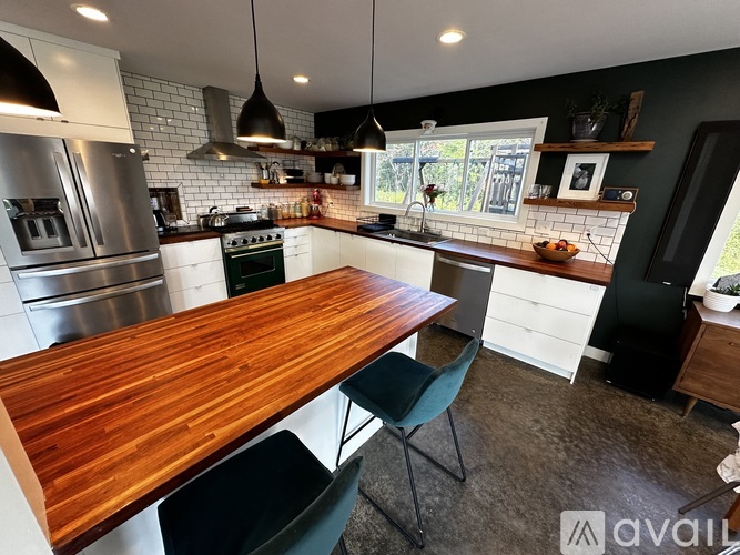 A kitchen with a wooden table and black chairs.