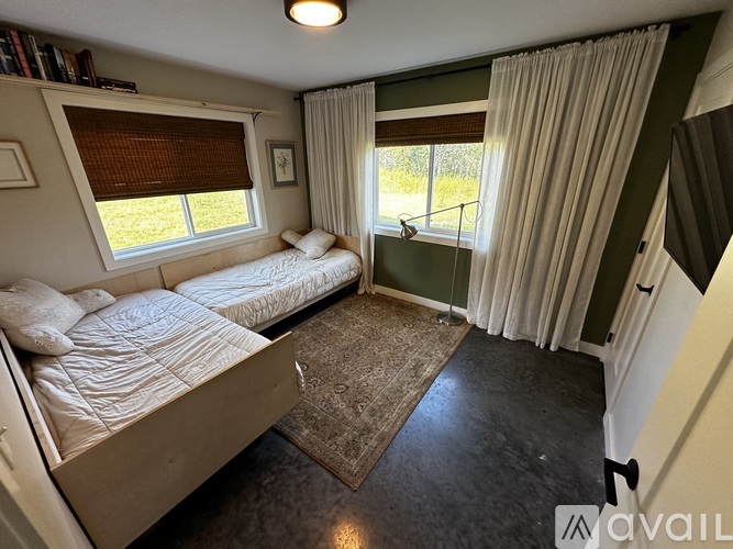 A bedroom with two beds and a window with curtains.
