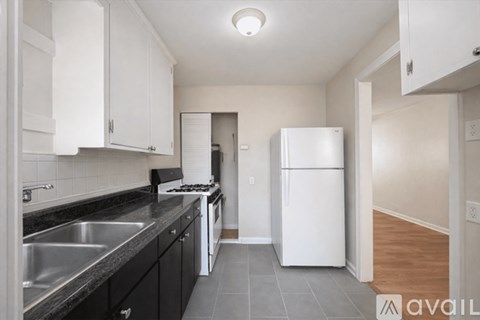 A kitchen with black cabinets and a white fridge.