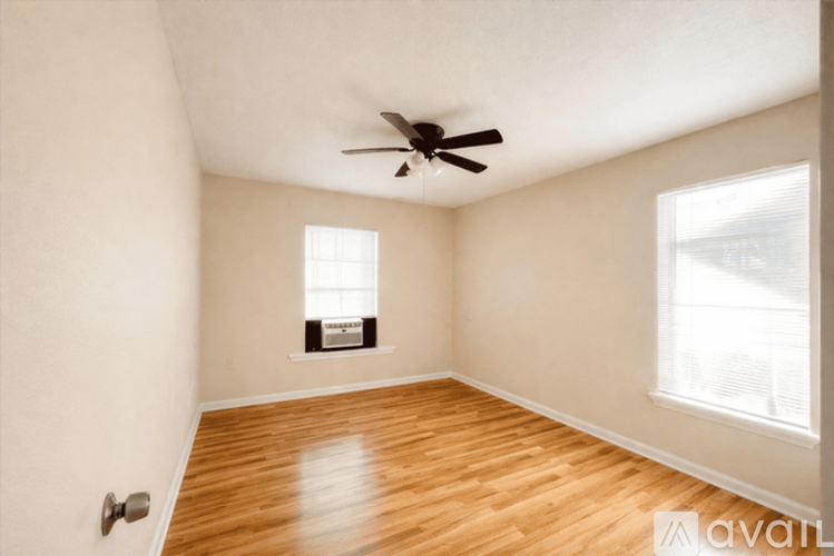 A room with a ceiling fan and wooden flooring.