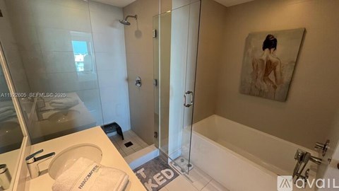 A bathroom with a bathtub, a shower, and a painting on the wall.