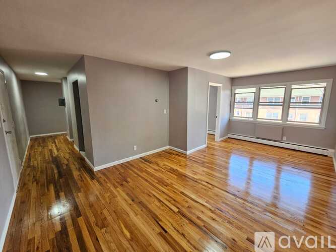 A room with wooden flooring and a window with a view of buildings outside.