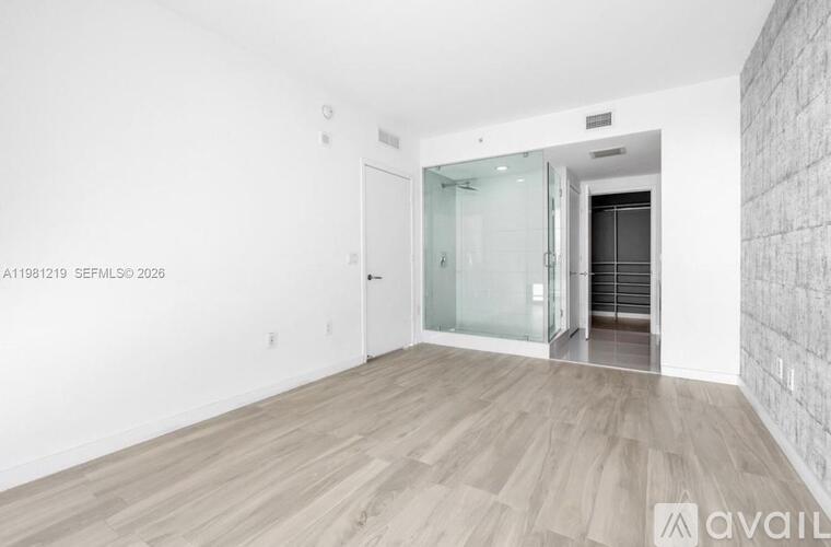 A room with wooden flooring and a glass door leading to another room.
