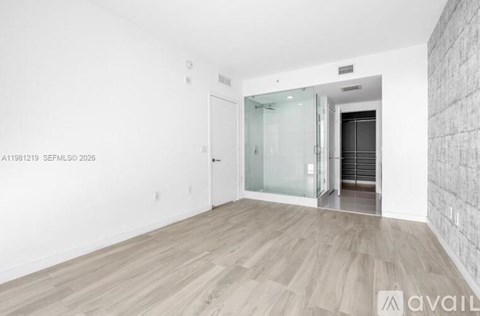A room with wooden flooring and a glass door leading to another room.