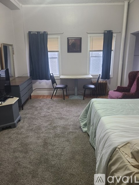 A bedroom with a bed, desk, chair, and window.