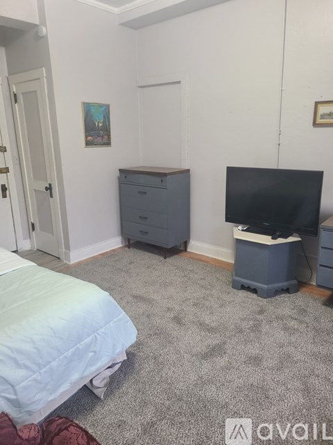 A bedroom with a bed, dresser, and a television.