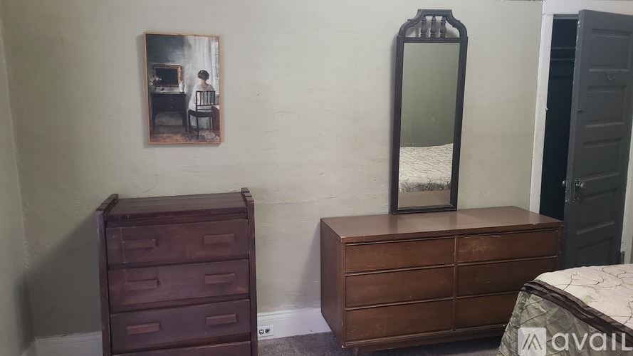 A brown chest of drawers sits next to a mirror in a room.
