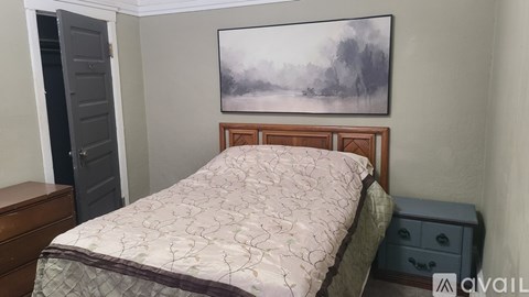 A bedroom with a bed, dresser, and a painting on the wall.
