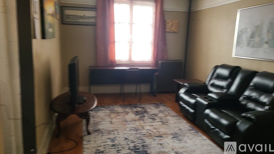 A living room with a black leather couch and a television.