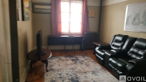 A living room with a black leather couch and a television.