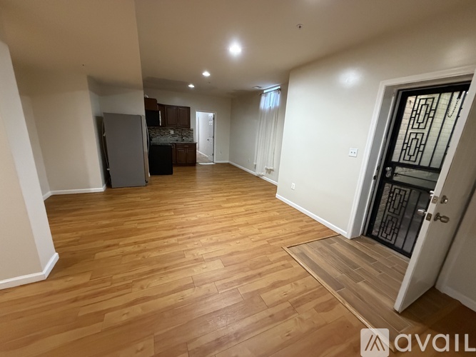 A spacious room with wooden flooring and a door on the right.