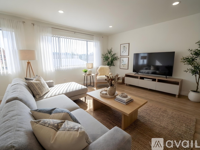 A living room with a grey sofa, a wooden coffee table, and a white cabinet with a television on it.