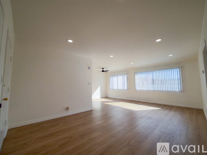 A spacious room with wooden flooring and white walls.