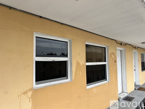 Two windows on a yellow wall with a view of trees outside.