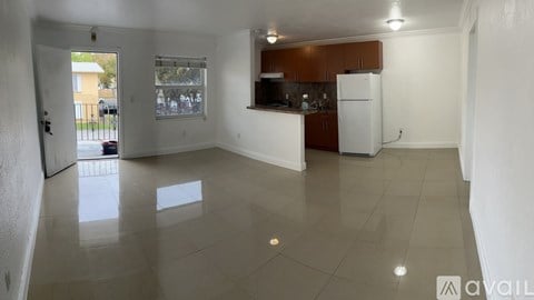 A kitchen area with a refrigerator, sink, and cabinets.