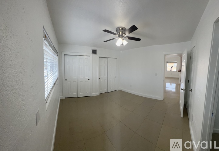 A spacious room with a ceiling fan and tiled floor.