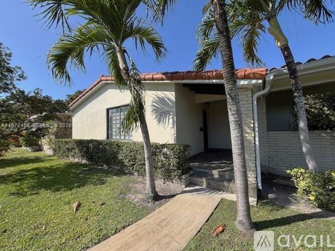 A house with a red tile roof and a palm tree in front.