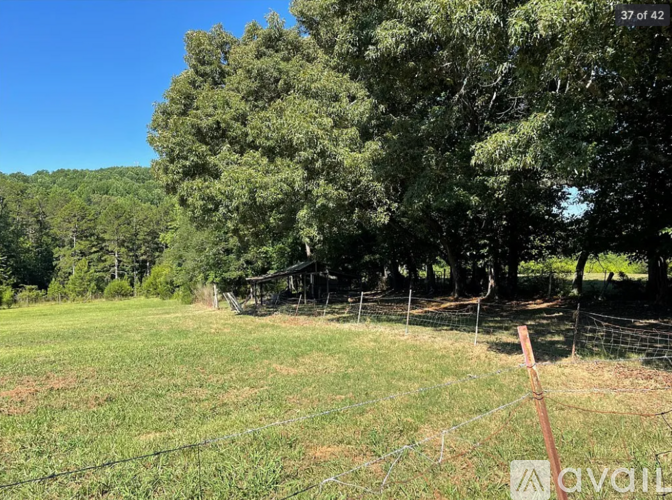 A field with a fence and trees in the background.