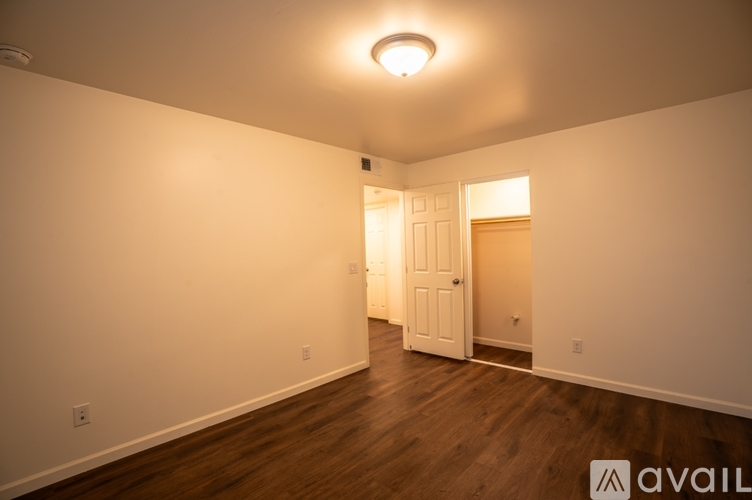 A room with a white door and wooden flooring.