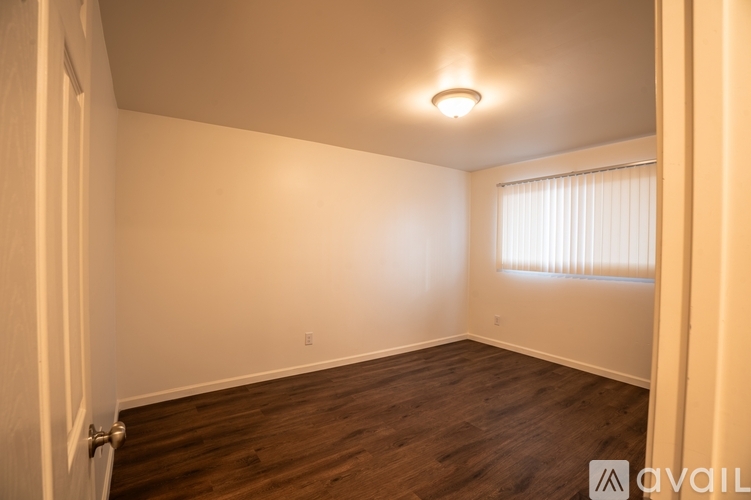 A room with wooden flooring and a window with blinds.