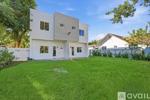 A modern white house with a large front yard.
