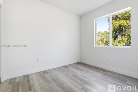 A room with a window showing trees outside.