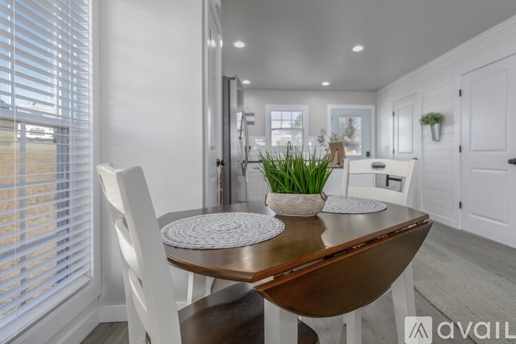 A modern dining room with a wooden table and white chairs.
