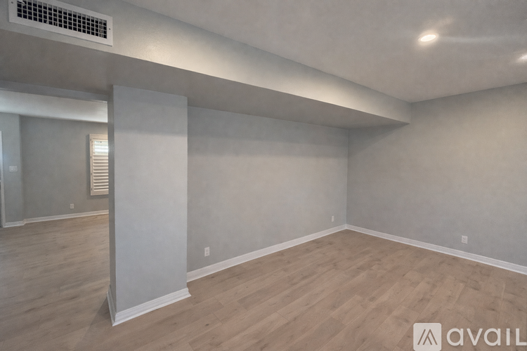 A spacious room with wooden flooring and white walls.