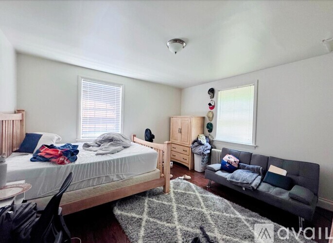 A bedroom with a bed, a couch, and a rug.