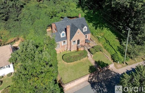A house with a large lawn and trees surrounding it.