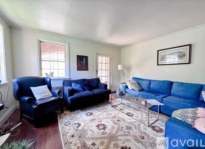 A living room with blue couches and a rug.