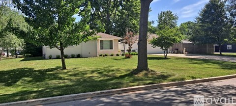 A house with a white fence and a tree in front of it.