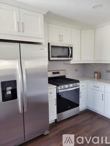 A kitchen with a stainless steel refrigerator and a microwave above the stove.