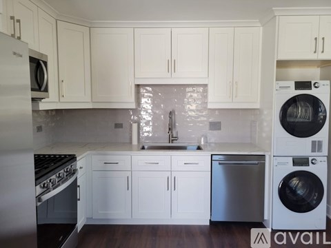 A kitchen with white cabinets and a stainless steel refrigerator.