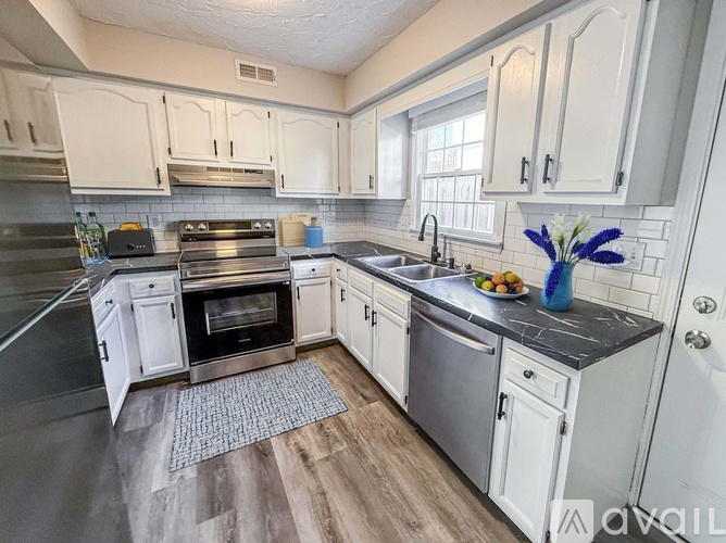 A kitchen with white cabinets and a black countertop.