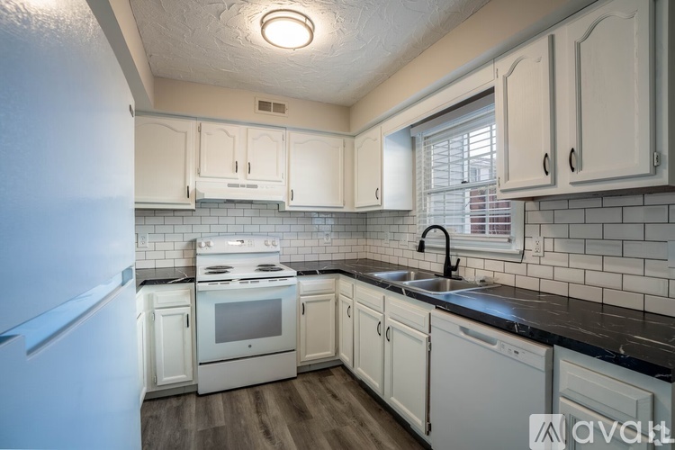 A kitchen with white cabinets and a black countertop.
