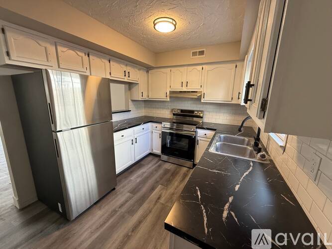 A kitchen with a black counter top and stainless steel appliances.