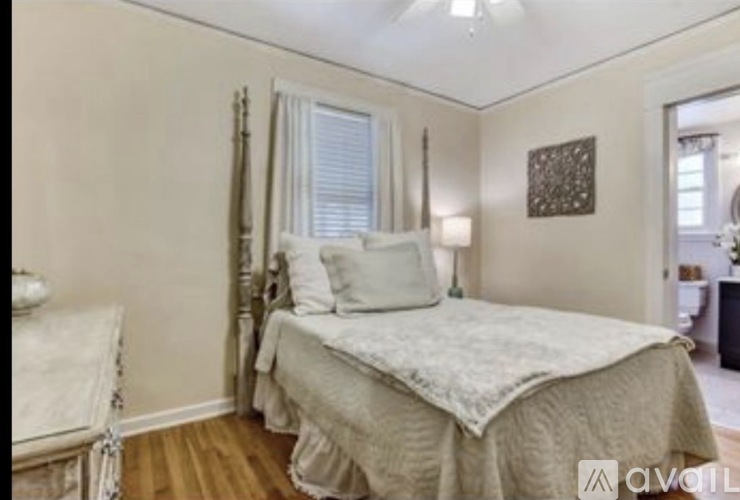 A bedroom with a bed, chair, and window.