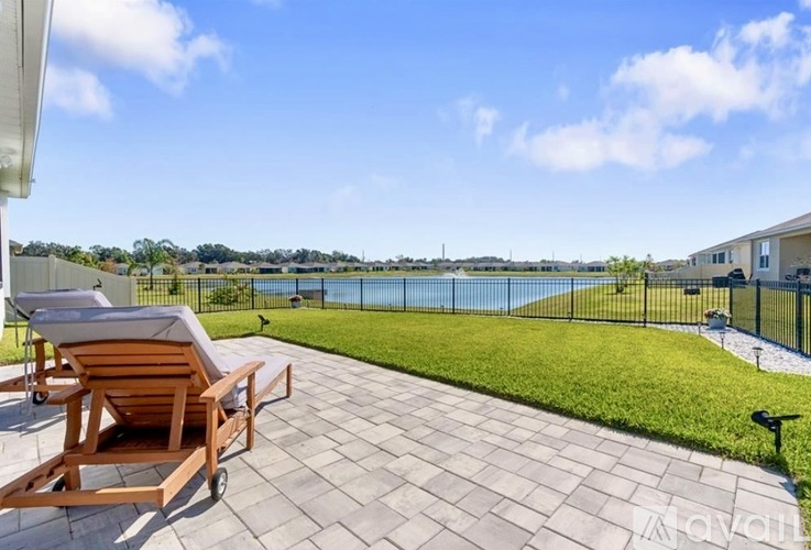 A patio with a chair and a table overlooking a pool.