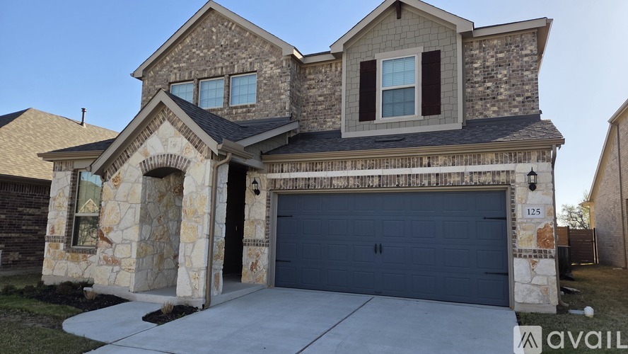 A two-story house with a garage and stone exterior.