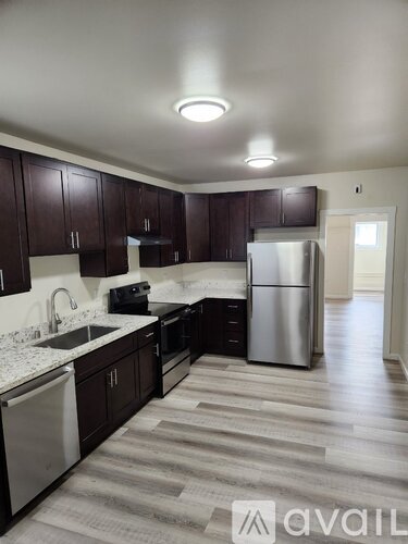 A kitchen with dark wood cabinets and a stainless steel refrigerator.